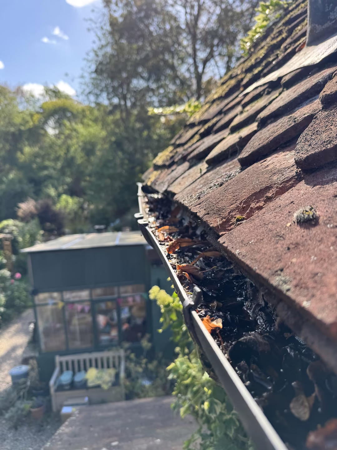 Gutter packed with leaves along a clay tile roof on a Just Jets gutter cleaning job in Essex